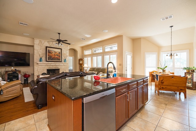 kitchen featuring dark stone counters, sink, a kitchen island with sink, stainless steel dishwasher, and decorative light fixtures