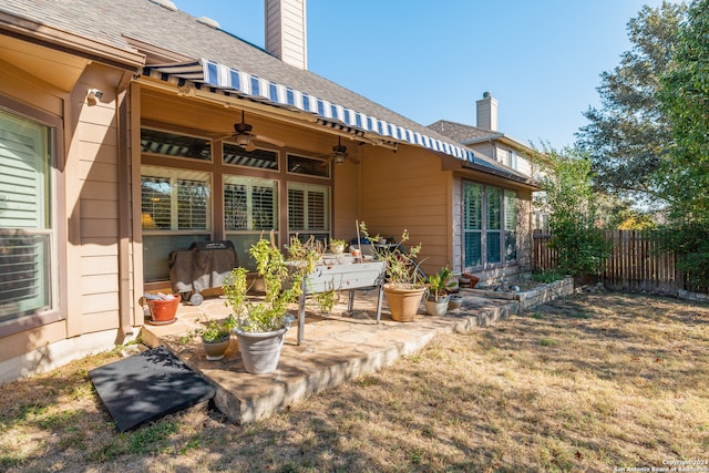 rear view of house featuring ceiling fan and a patio area