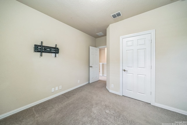 unfurnished bedroom with a textured ceiling and light carpet