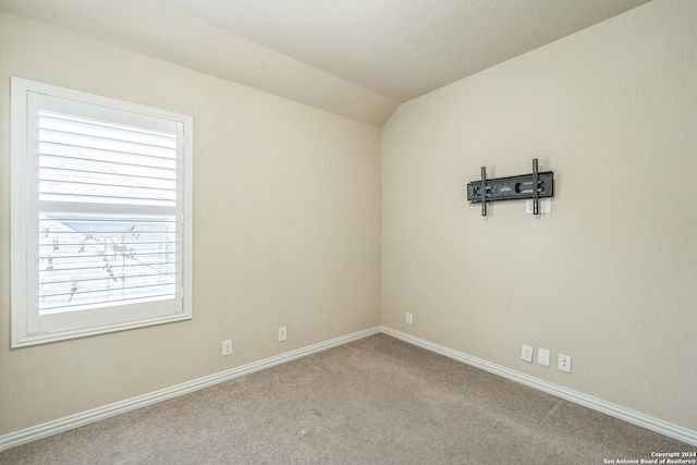 spare room featuring lofted ceiling and carpet