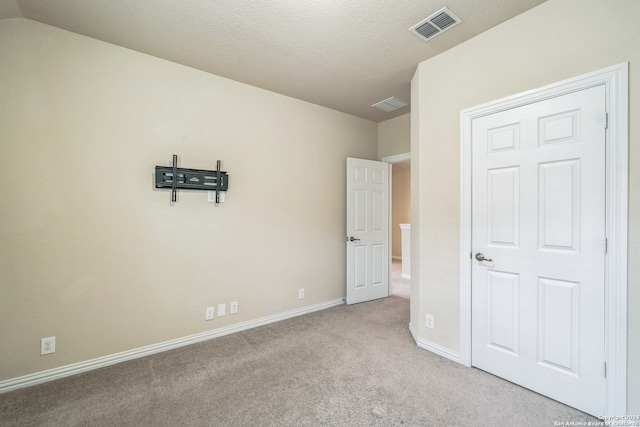 unfurnished bedroom with a textured ceiling and light carpet