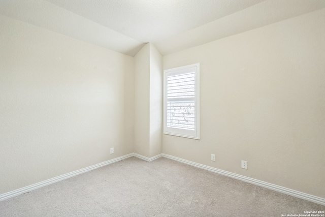 carpeted spare room featuring lofted ceiling