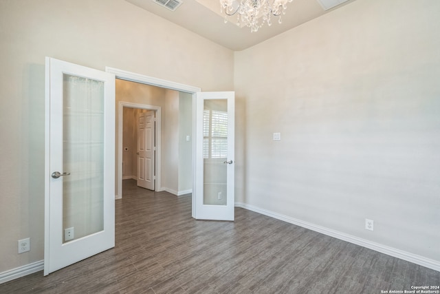 unfurnished room featuring dark wood-type flooring, a chandelier, and french doors