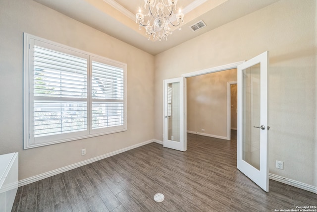 spare room with ornamental molding, french doors, a notable chandelier, and dark hardwood / wood-style floors