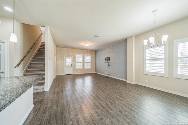 unfurnished living room with dark hardwood / wood-style floors, plenty of natural light, and a notable chandelier