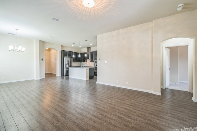 unfurnished living room featuring dark wood-type flooring and a chandelier