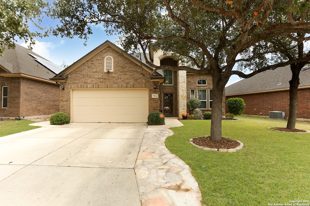 view of front of property featuring a garage, central AC, and a front lawn