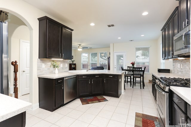 kitchen featuring stainless steel appliances, backsplash, light tile patterned floors, sink, and ceiling fan