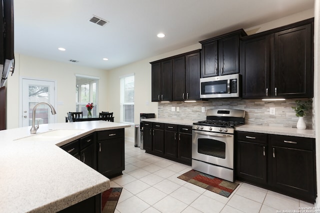 kitchen featuring tasteful backsplash, appliances with stainless steel finishes, sink, and light tile patterned flooring