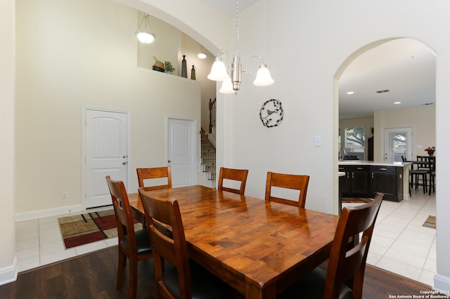 dining space featuring light hardwood / wood-style flooring, a chandelier, and a high ceiling