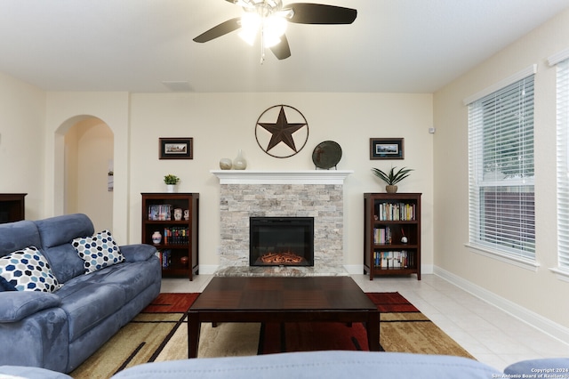 tiled living room with ceiling fan and a fireplace