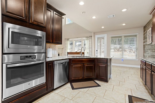 kitchen featuring a wealth of natural light, stainless steel appliances, and light stone counters