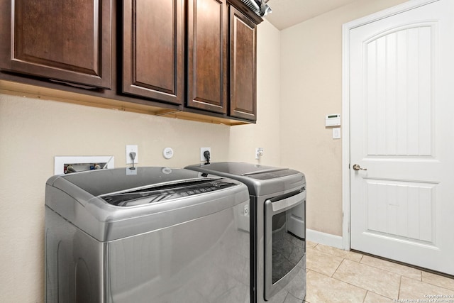 clothes washing area featuring light tile patterned floors, cabinets, and washing machine and clothes dryer