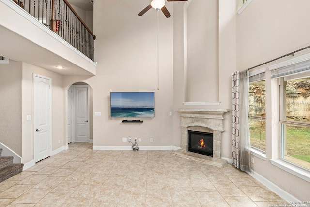 unfurnished living room featuring a high ceiling, ceiling fan, and light tile patterned floors