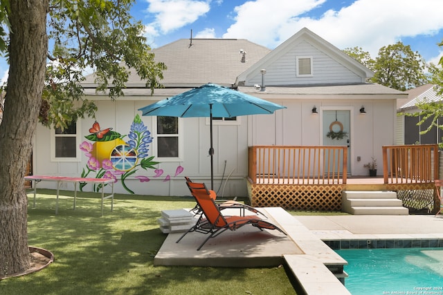 rear view of house featuring a lawn and a pool side deck