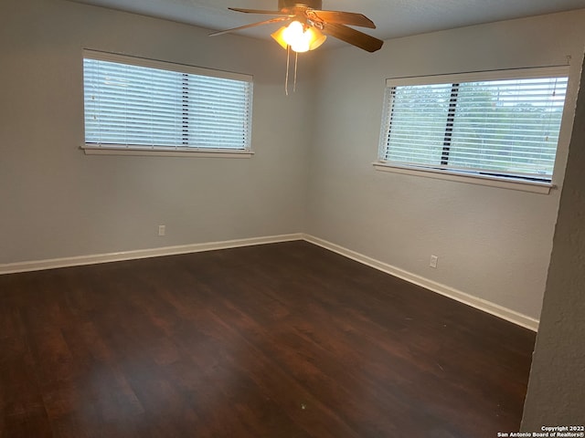 empty room with ceiling fan and dark hardwood / wood-style flooring