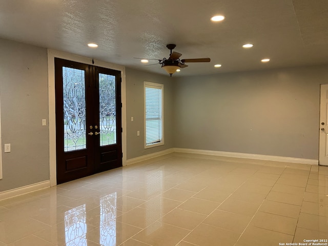 tiled entrance foyer with french doors, ceiling fan, and a textured ceiling