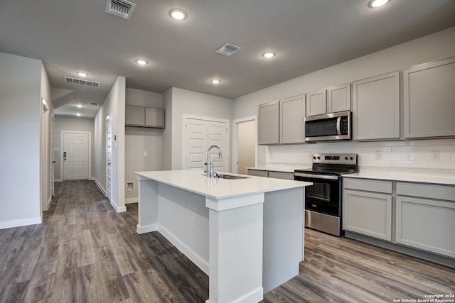 kitchen with a center island with sink, stainless steel appliances, sink, and gray cabinetry