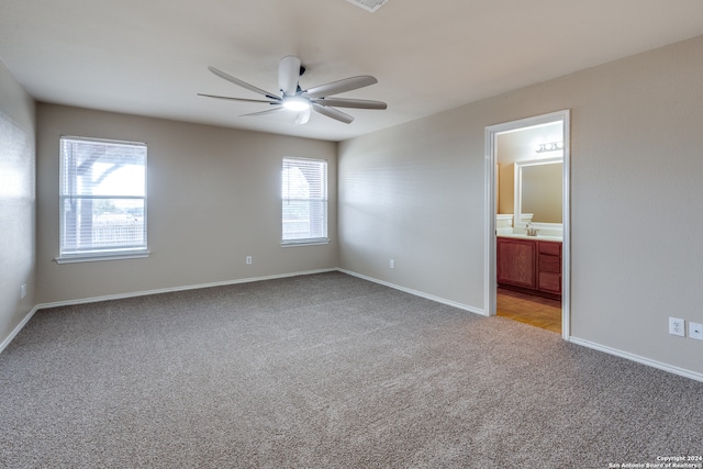 carpeted spare room with ceiling fan, sink, and a healthy amount of sunlight