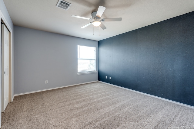 empty room featuring ceiling fan and carpet