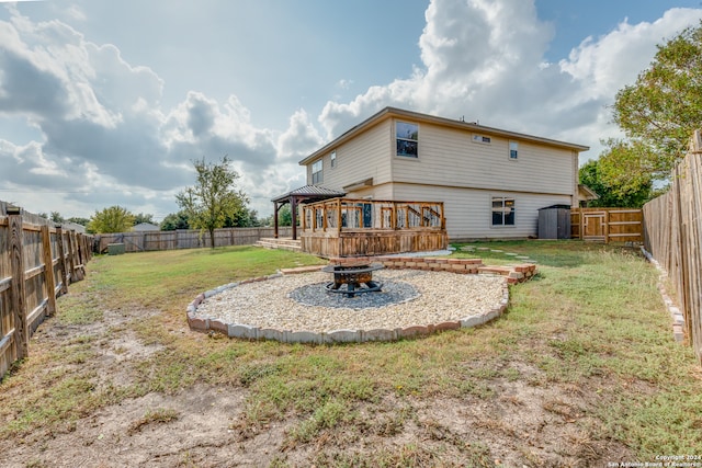 rear view of property with a deck, a yard, and a fire pit