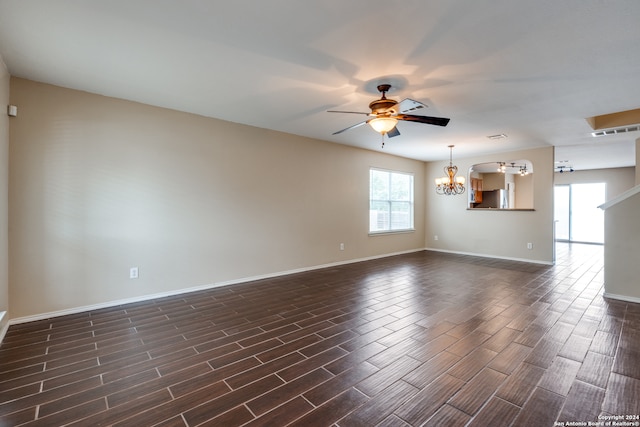 empty room with dark wood-type flooring and ceiling fan with notable chandelier