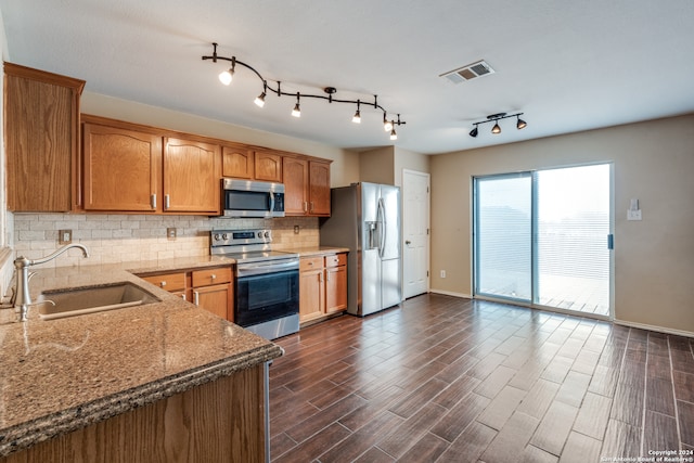 kitchen featuring dark wood-type flooring, sink, backsplash, light stone countertops, and appliances with stainless steel finishes