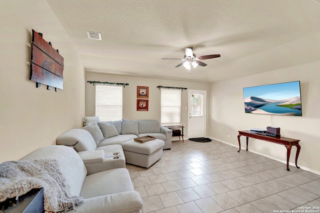 living room with a textured ceiling, ceiling fan, and light tile patterned floors