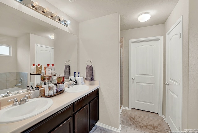 bathroom featuring a tub to relax in, vanity, a textured ceiling, and tile patterned flooring