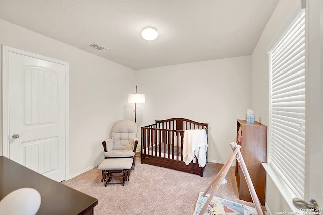 bedroom featuring light carpet and a nursery area