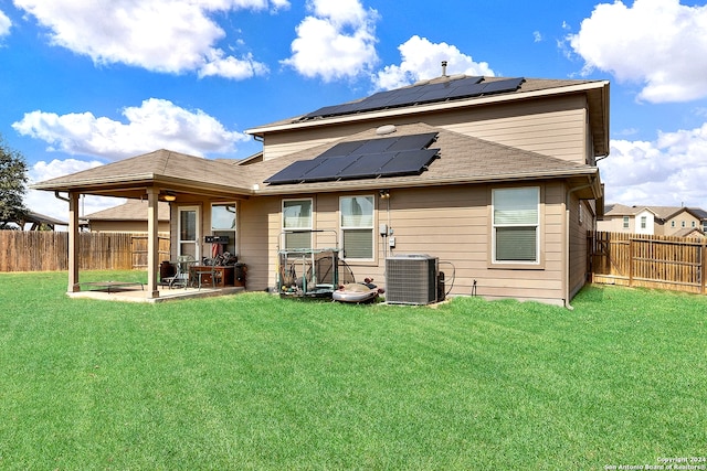 back of property with central AC unit, a lawn, solar panels, and a patio