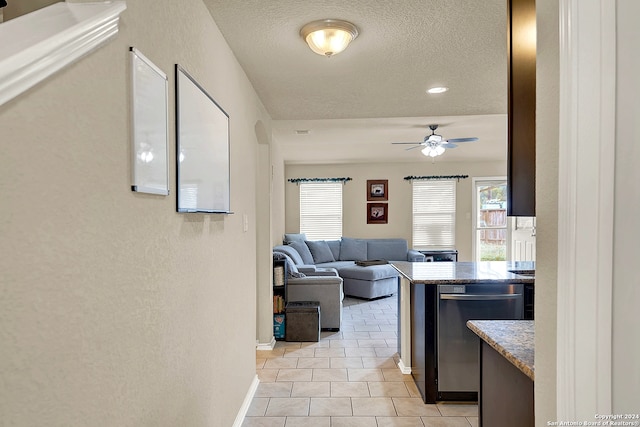 interior space with light tile patterned flooring, stainless steel dishwasher, a textured ceiling, and ceiling fan