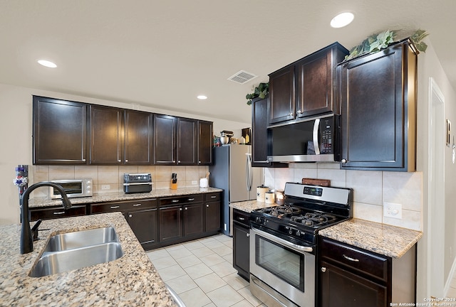 kitchen with dark brown cabinetry, appliances with stainless steel finishes, sink, and tasteful backsplash