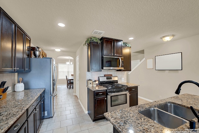 kitchen featuring light stone countertops, a textured ceiling, sink, and appliances with stainless steel finishes