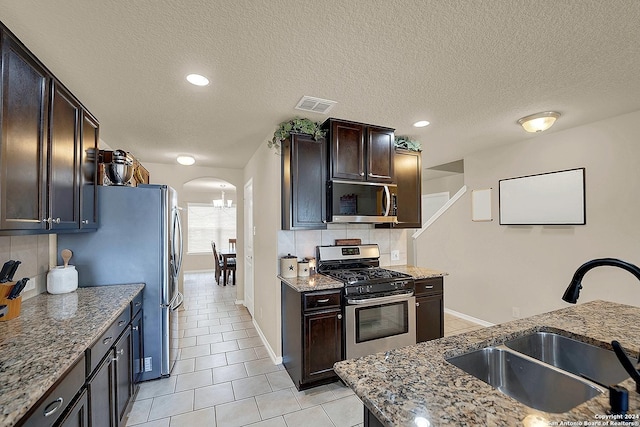 10055 Strasbourg Way, Schertz, TX 78154 - kitchen featuring appliances with stainless steel finishes, a sink, arched walkways, light tile patterned floors, and tasteful backsplash