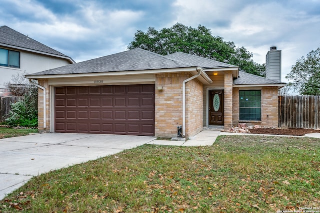 ranch-style home featuring a garage and a front lawn