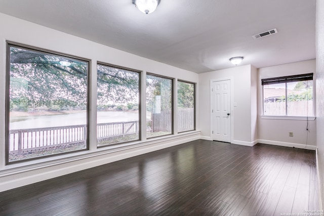 spare room with dark wood-type flooring and a water view