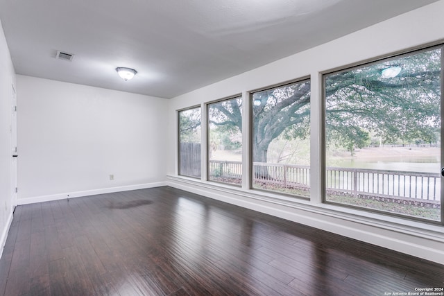 unfurnished room with a water view, wood-type flooring, and plenty of natural light