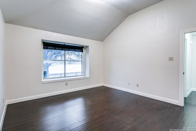 empty room with dark wood-type flooring and lofted ceiling