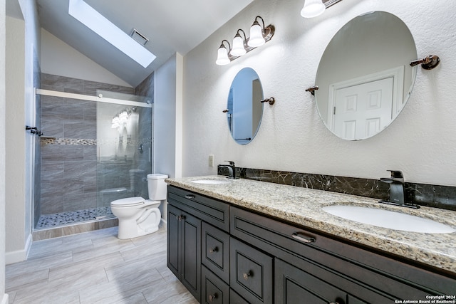 bathroom with toilet, vaulted ceiling with skylight, vanity, and a shower with door