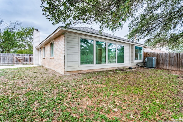 rear view of house featuring central air condition unit and a yard