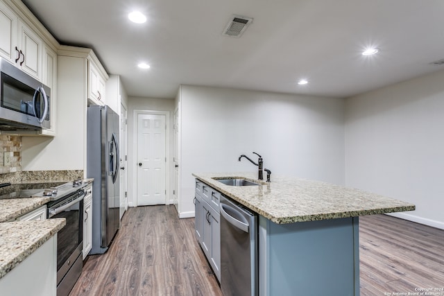 kitchen featuring a center island with sink, stainless steel appliances, dark hardwood / wood-style floors, light stone countertops, and sink