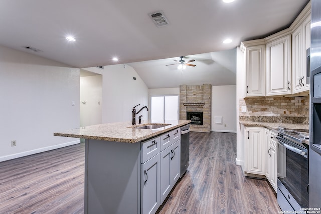 kitchen featuring dark hardwood / wood-style flooring, vaulted ceiling, sink, a kitchen island with sink, and appliances with stainless steel finishes