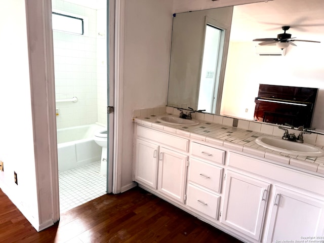 bathroom featuring toilet, hardwood / wood-style flooring, vanity, ceiling fan, and an AC wall unit