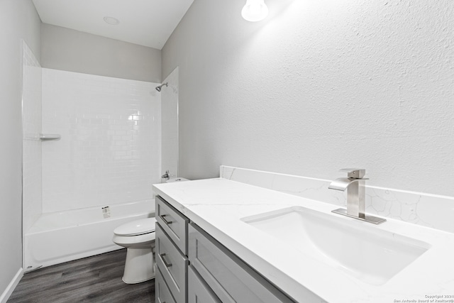 full bathroom with hardwood / wood-style floors, washtub / shower combination, vanity, and toilet