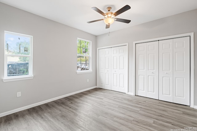 unfurnished bedroom featuring multiple closets, ceiling fan, and light hardwood / wood-style floors