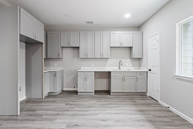 kitchen with light hardwood / wood-style floors, sink, and gray cabinetry