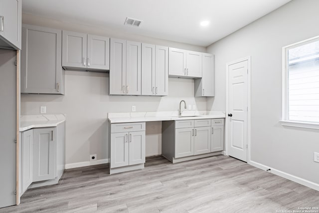 kitchen with light hardwood / wood-style floors, sink, and gray cabinetry