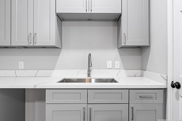 kitchen with gray cabinets, sink, and light stone countertops