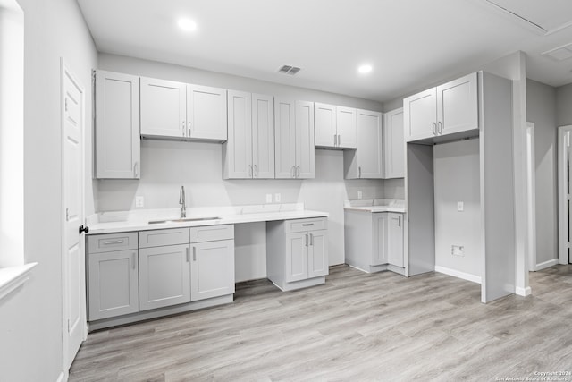 kitchen with gray cabinetry, sink, and light wood-type flooring